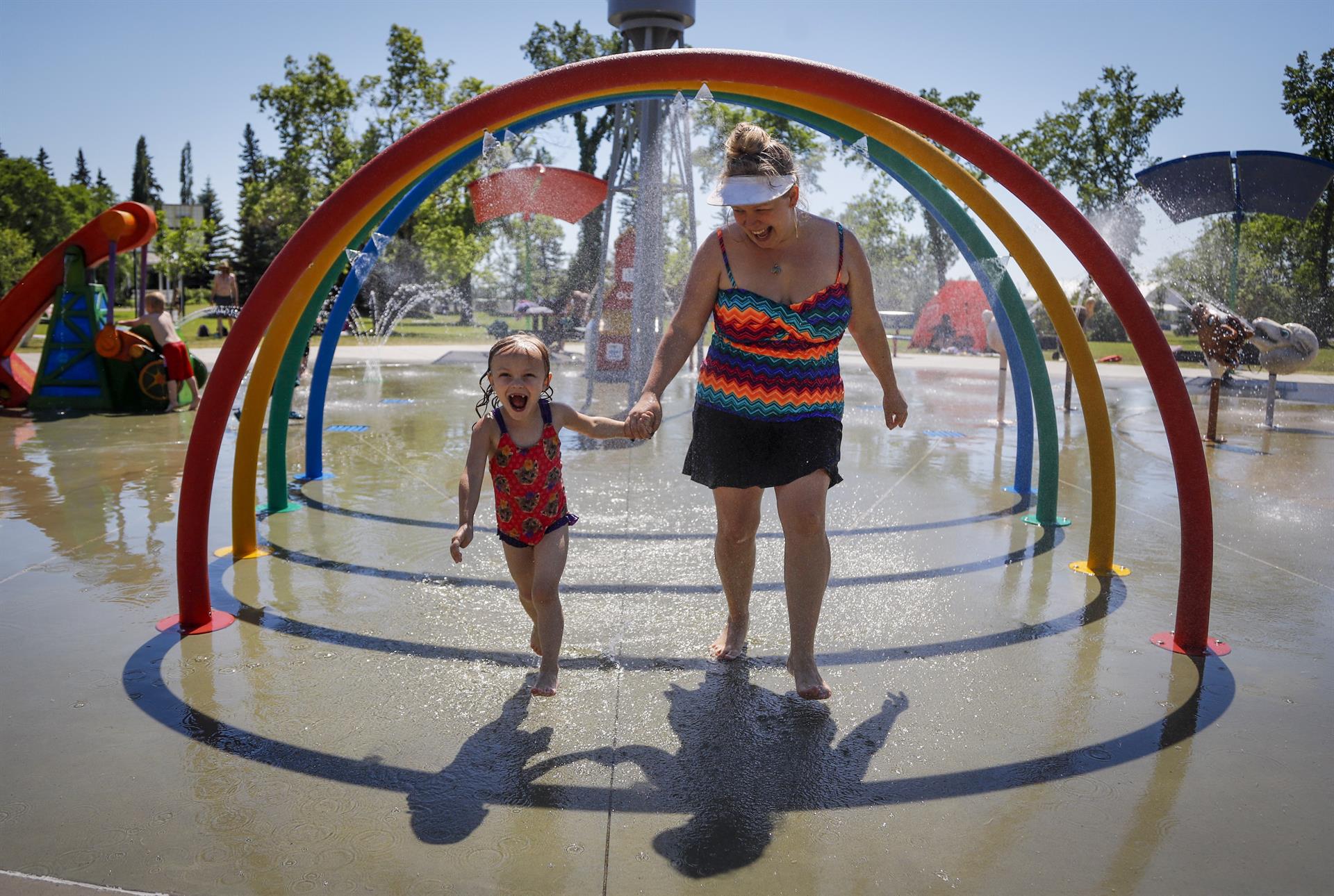 Una madre y su hija corren entre aspersores para tratar de vencer el calor intenso que azota Canadá / Foto: EP