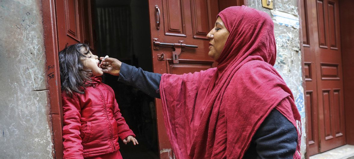 Una trabajadora sanitaria vacuna a una niña de 4 años contra la polio en la puerta de su casa. Ahora la erradicación de la polio estaría en peligro / Foto: Asad Zaidi - UNICEF - News.un.org