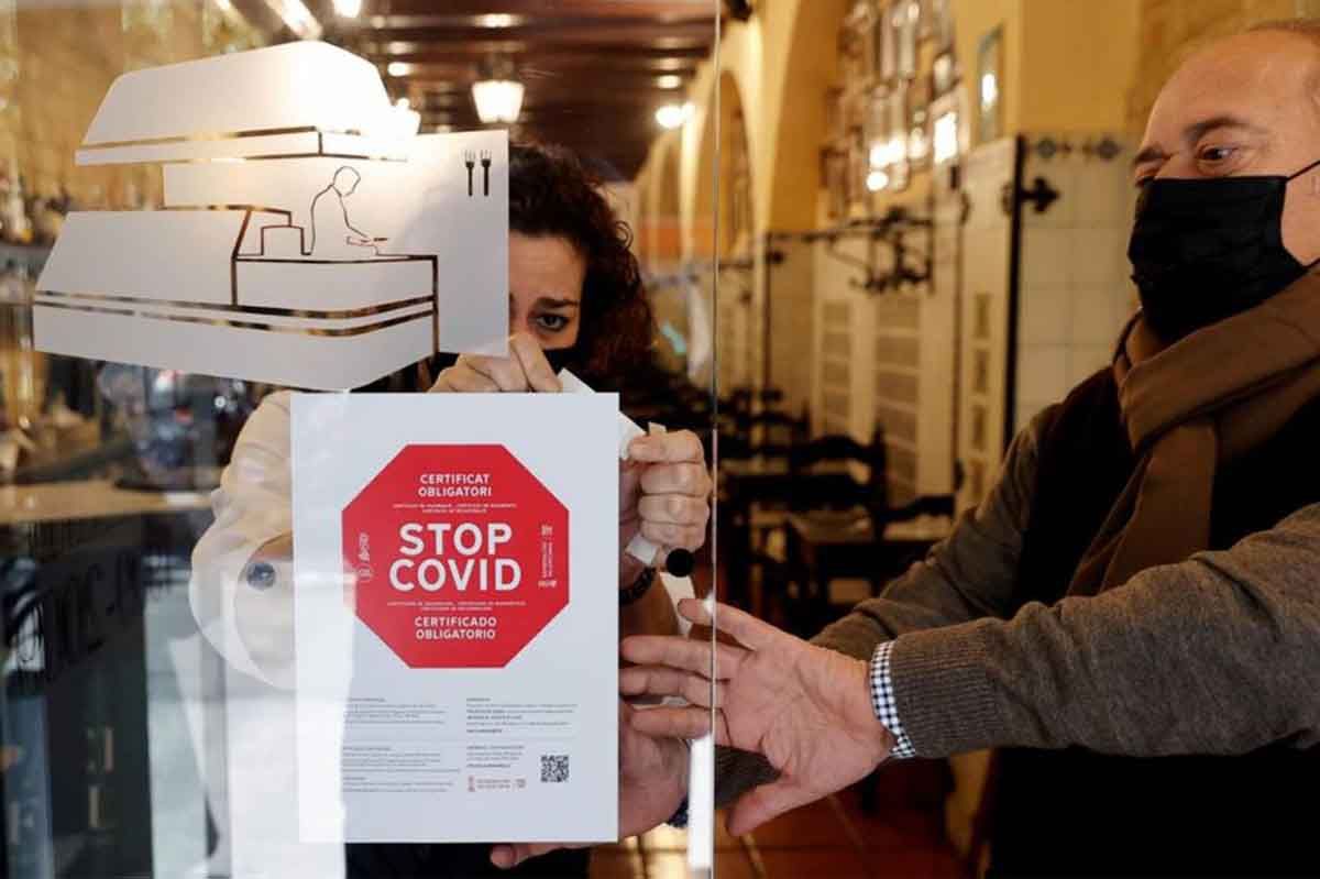 Personal de un hotel coloca un cartel a la entrada de su restaurante avisando de la obligatoriedad del pasaporte covid / Foto: SINC