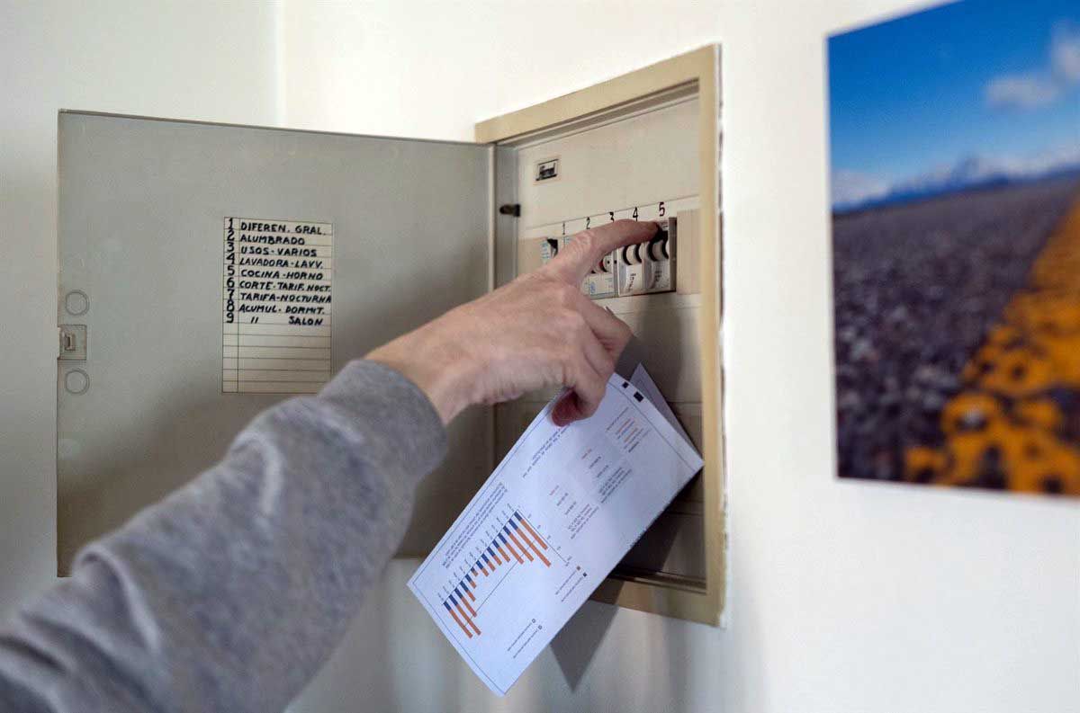 Una persona sube los plomos de la luz con una factura de luz en la mano, a 3 de enero de 2022, en Madrid