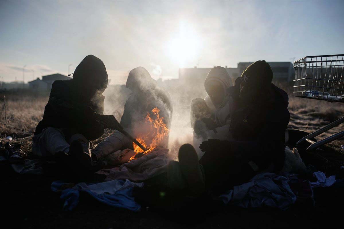 Un grupo de personas ghanesas preparan una hoguera en Medyka, frontera de Polonia con Ucrania / Foto: EP