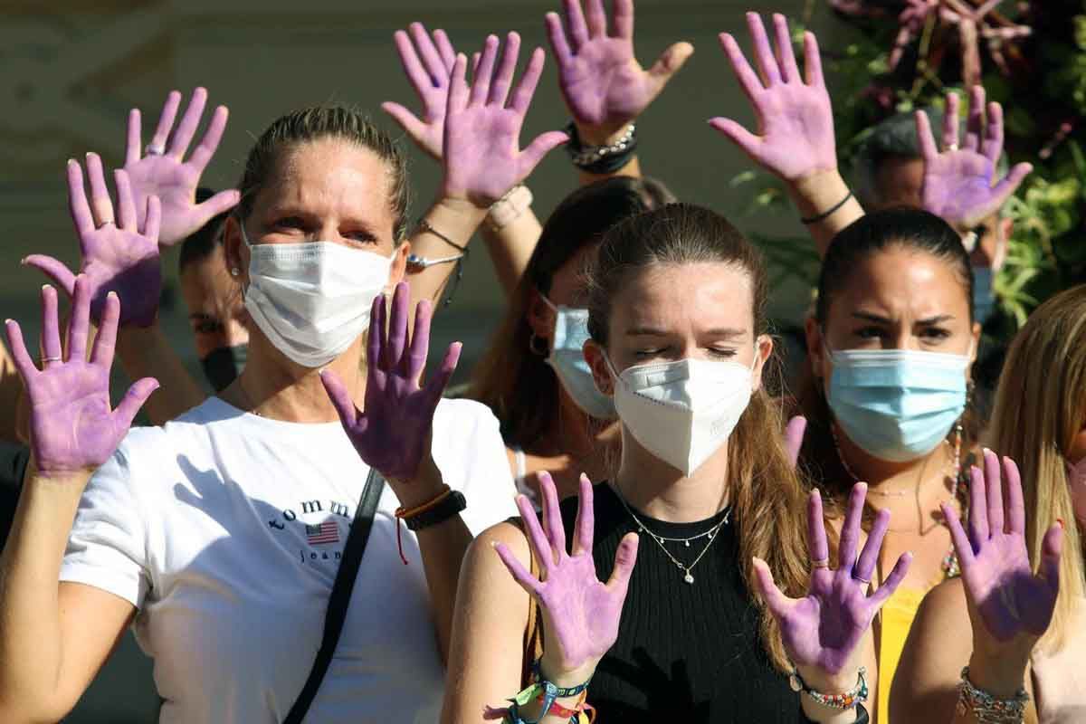Un grupo de mujeres con las manos moradas guarda un minuto de silencio en Málaga por una víctima mortal de violencia de género