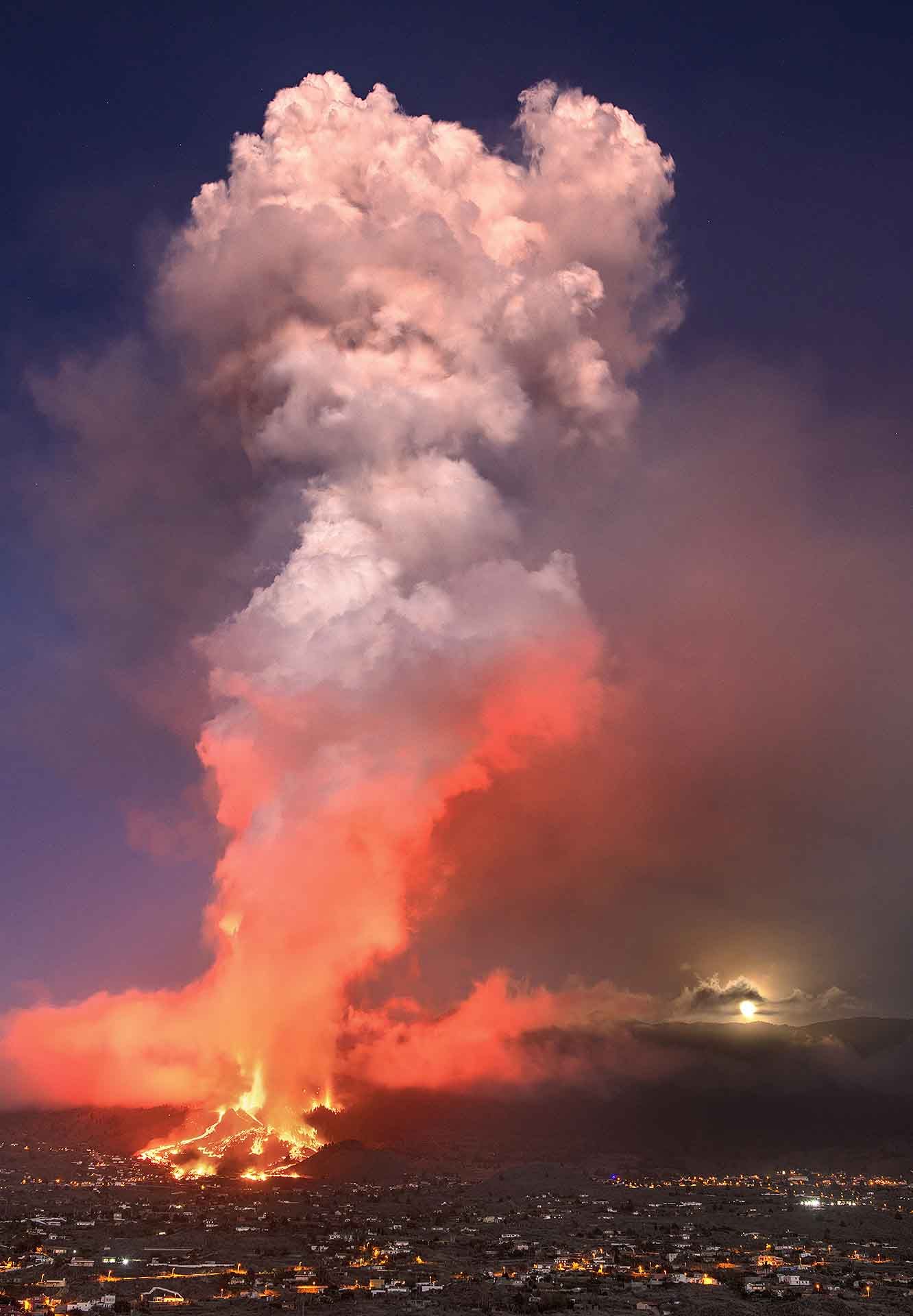 Vista de la columna eruptiva del volcán de La Palma en sus primeras horas arrasando el barrio de El Paraíso (El Paso), mientras la luna llena sale detrás de la montaña (Canarias) / Foto: Saul Santos