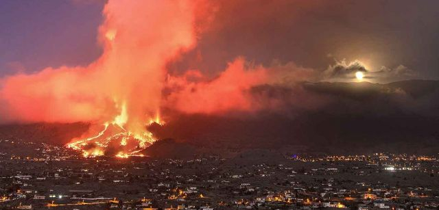 Vista de la columna eruptiva del volcán de La Palma en sus primeras horas arrasando el barrio de El Paraíso (El Paso), mientras la luna llena sale detrás de la montaña (Canarias) / Foto: Saul Santos