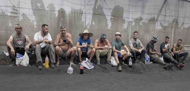 Un grupo de trabajadores comen y descansan durante una dura jornada de retirada de cenizas en los invernaderos en Isla de La Palma (Canarias) / Foto: Saul Santos