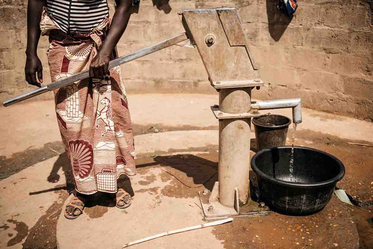 Una mujer impulsa la bomba manual de un pozo ya instalado por AUARA. La escasez de agua en África / Foto: AUARA - EP