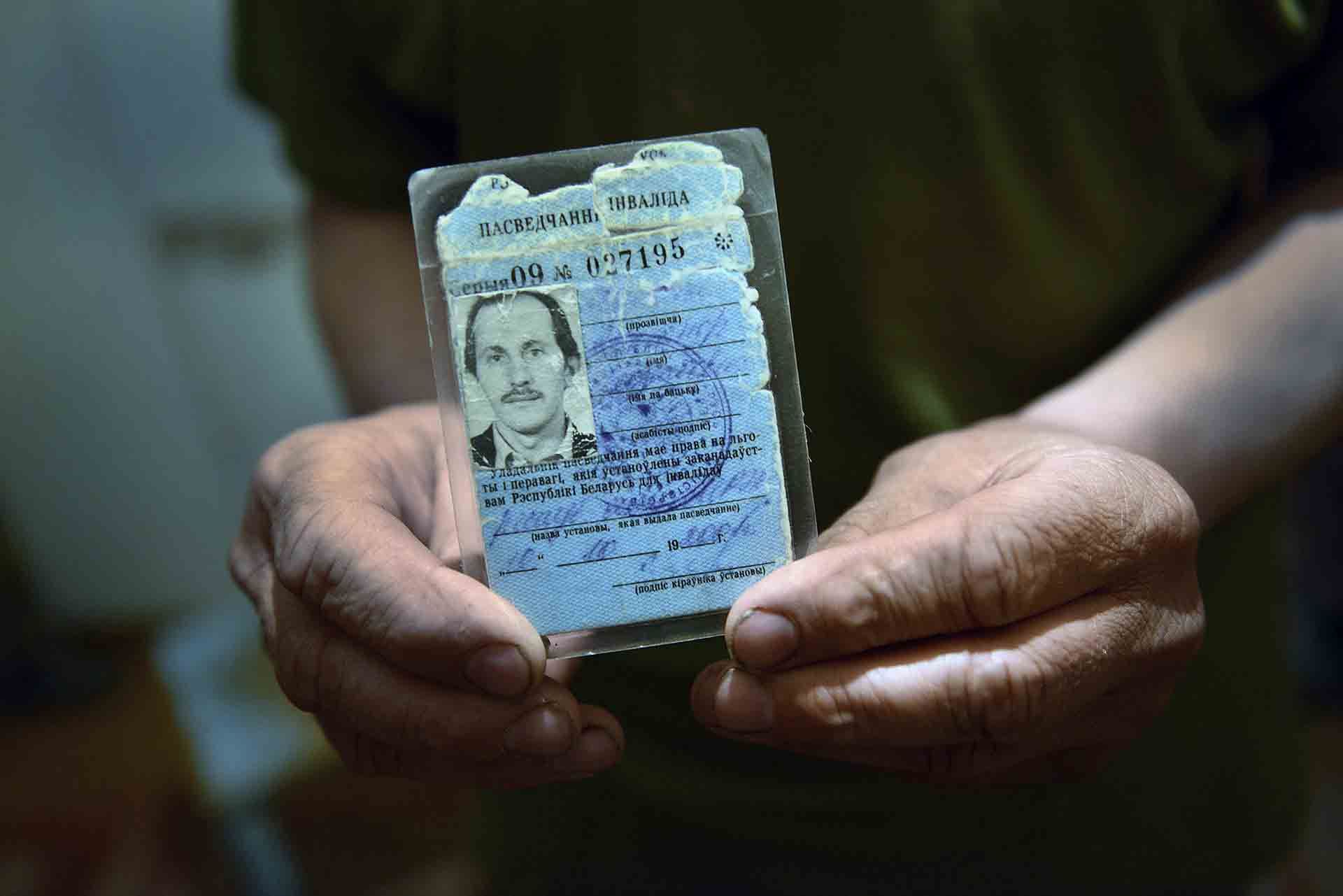 Alexander muestra su tarjeta de discapacidad al 100% otorgada por el gobierno a causa de la radiación. Aún así nunca llegó toda la ayuda que la administración prometió a los afectados / Foto: Alfons Rodríguez