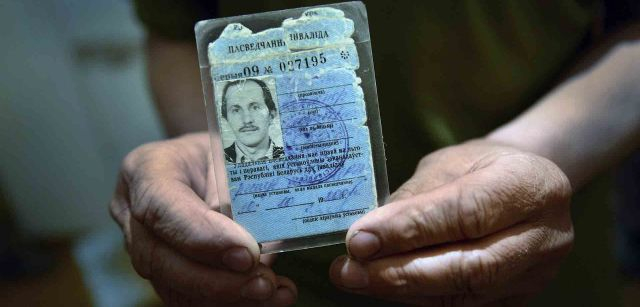 Alexander muestra su tarjeta de discapacidad al 100% otorgada por el gobierno a causa de la radiación. Aún así nunca llegó toda la ayuda que la administración prometió a los afectados / Foto: Alfons Rodríguez