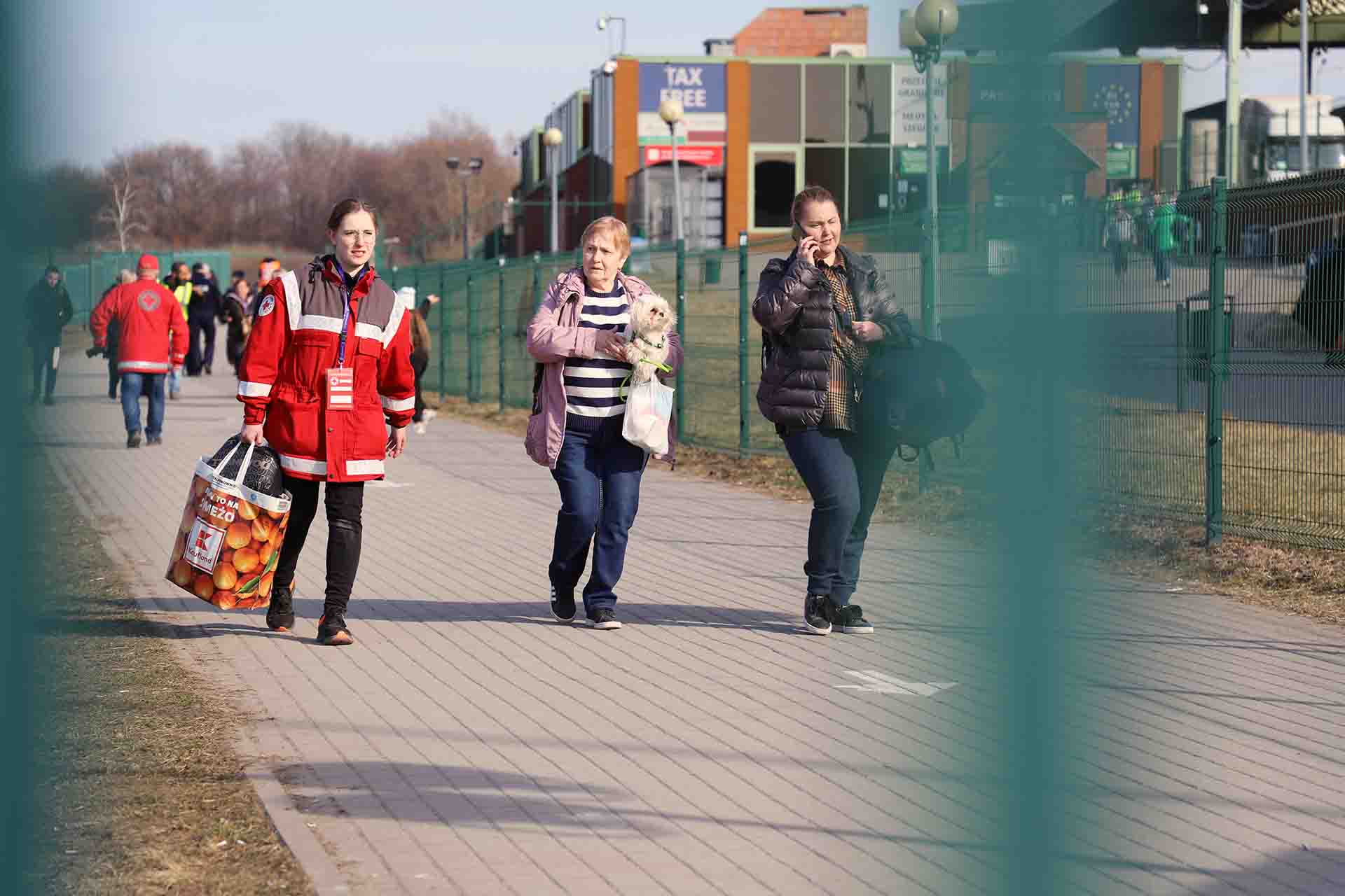 Dos mujeres ucranianas a punto de cruzar la berja de la frontera que separa Ucrania con Polonia, acompañadas por una voluntaria de la Cruz Roja / Foto: FFM - EA