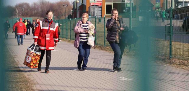 Dos mujeres ucranianas a punto de cruzar la berja de la frontera que separa Ucrania con Polonia, acompañadas por una voluntaria de la Cruz Roja / Foto: FFM - EA