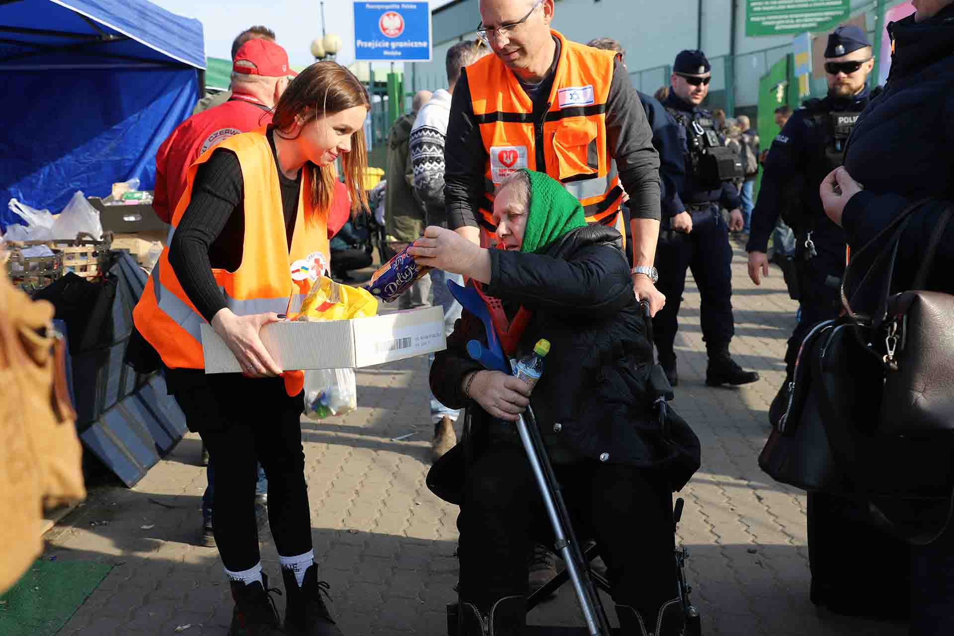 Una mujer mayor recibe un paquete de galletas de una voluntaria de la Cruz Roja / Foto: FFM - EA