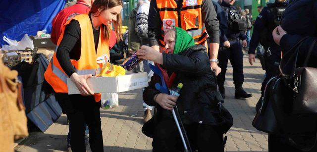 Una mujer mayor recibe un paquete de galletas de una voluntaria de la Cruz Roja / Foto: FFM - EA