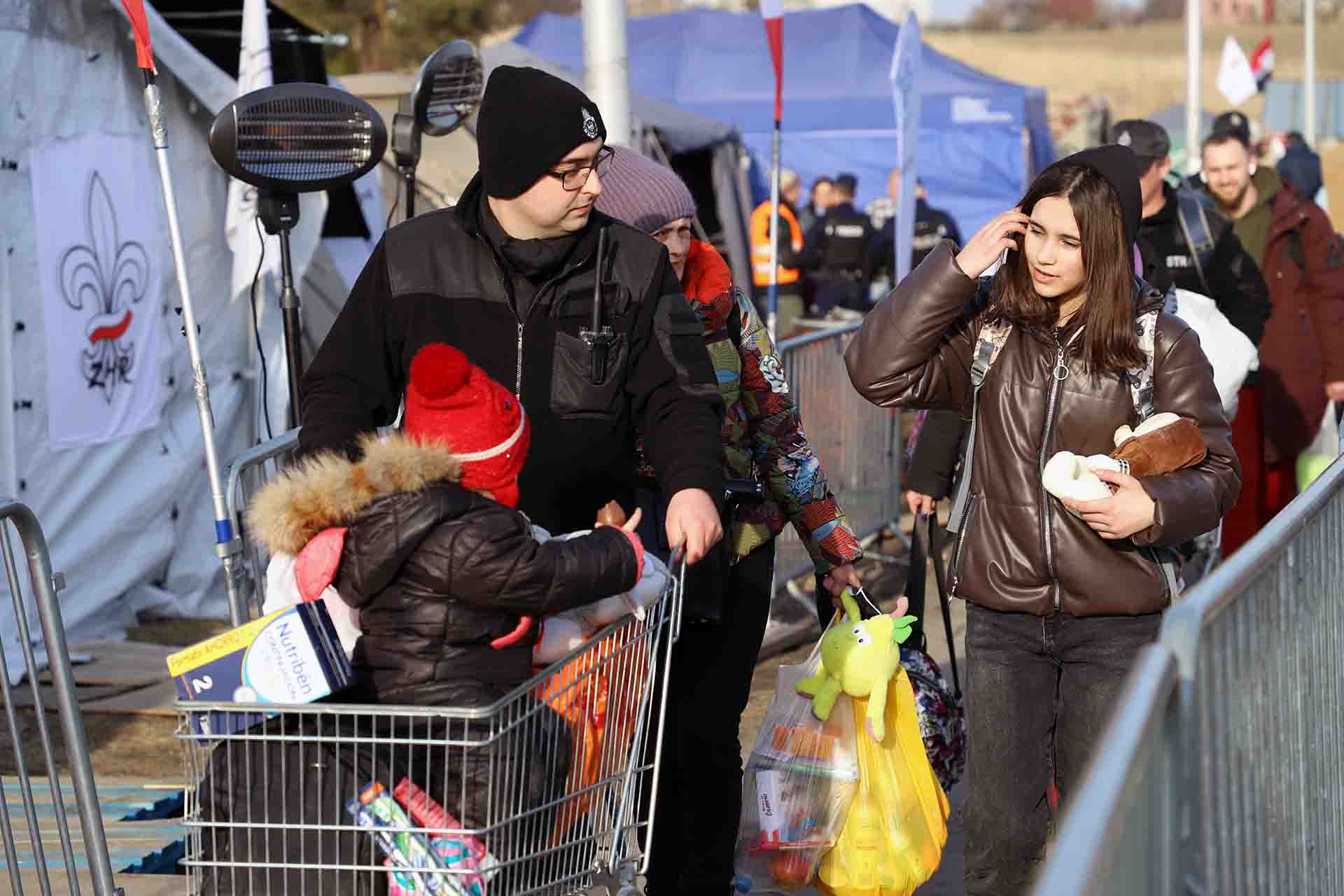 Una familia de personas refugiadas ucranianas cruza un paso repleto de carpas y tiendas en Medyka, Polonia / Foto: FFM - EA