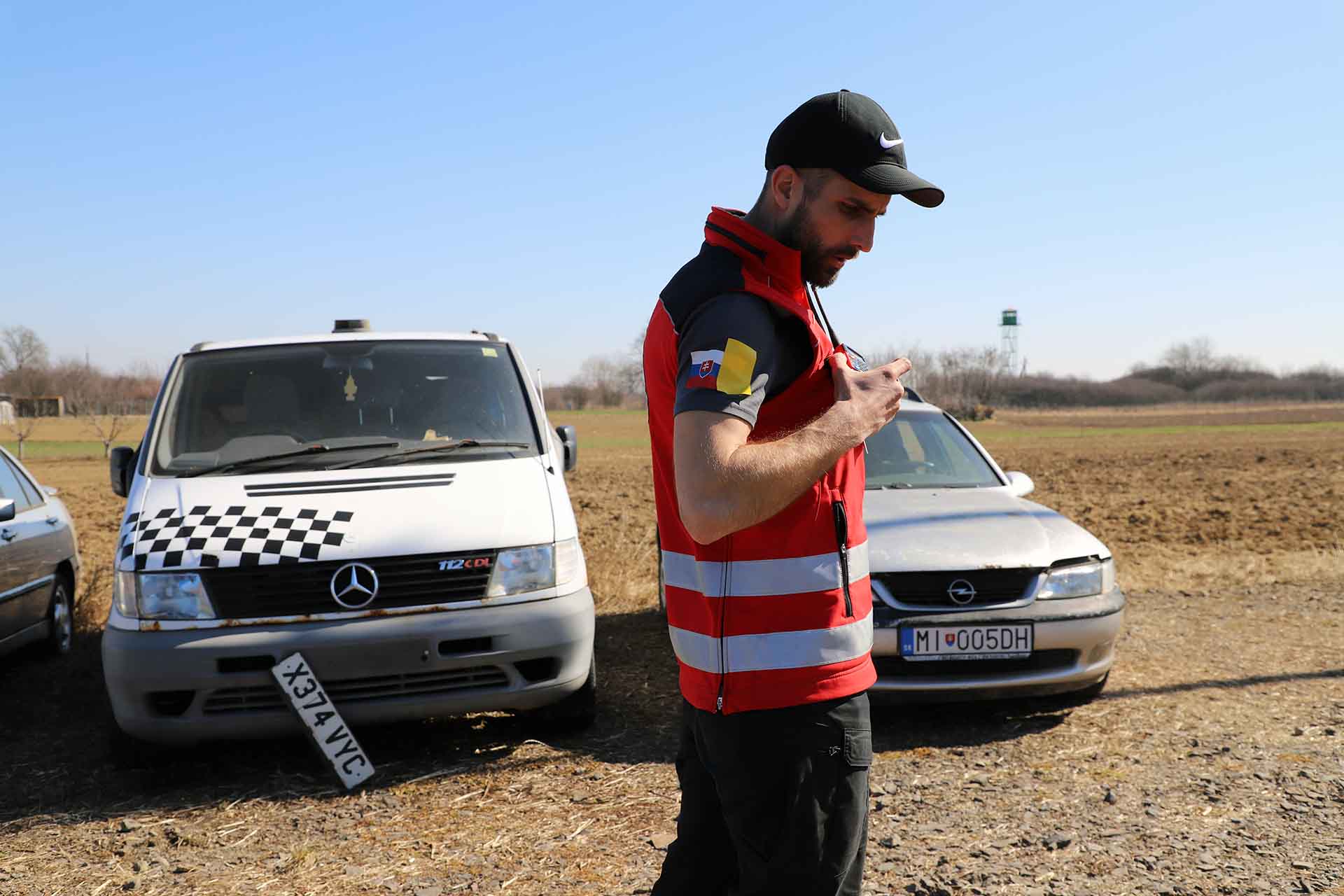 El voluntario de la Cruz Roja Eslovaca, Stanislav Zupka, habla por radio junto a una furgoneta venida de Ucrania en un estado defectuoso, con una torre de vigilancia de la frontera con Ucrania / Foto: FFM - EA