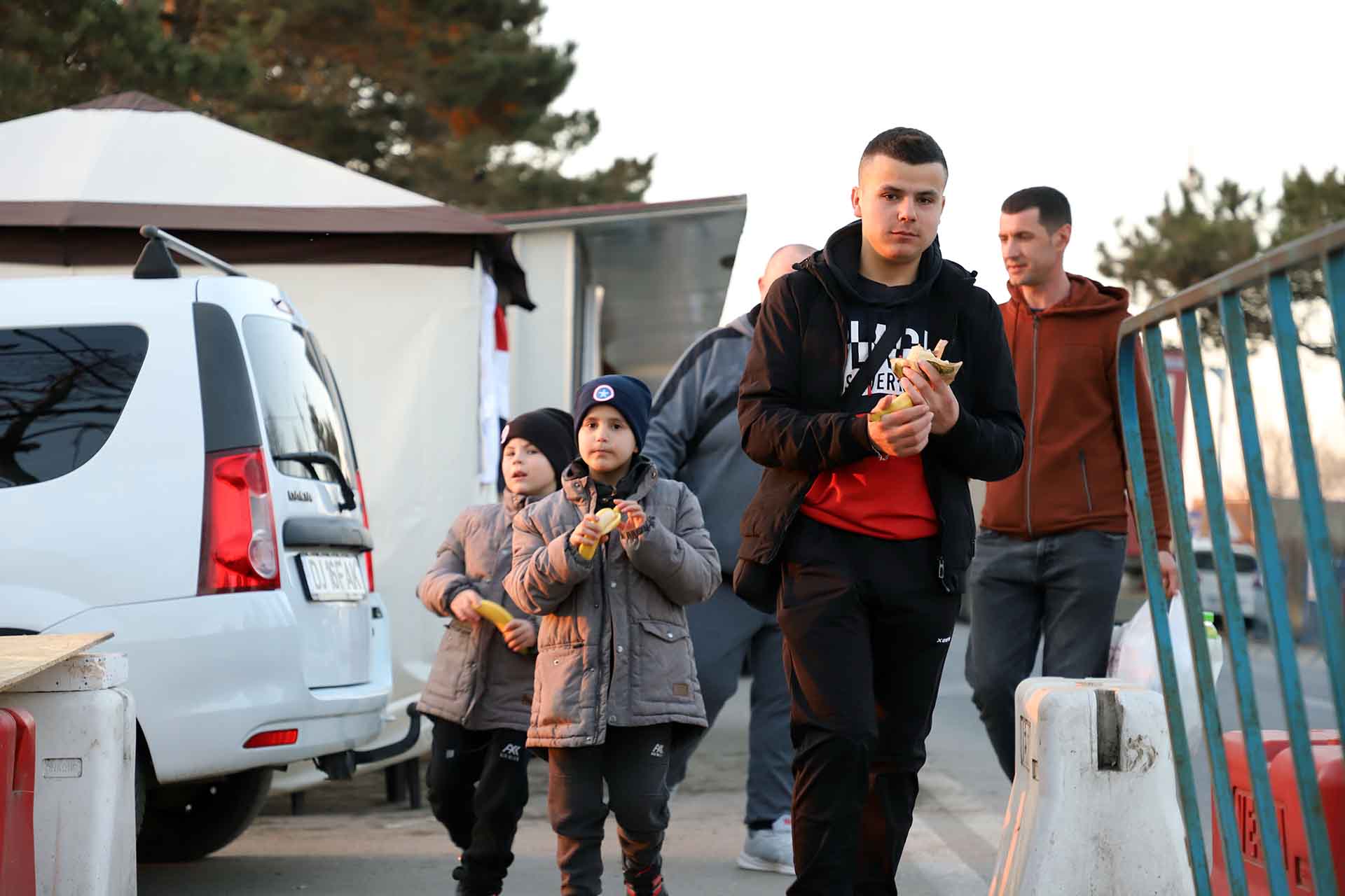 Un adolescente y dos niños caminan mientras comen unos bocadillos que les han brindado en una de las muchas carpas de servicios en Siret (Rumanía) / Foto: FFM - EA