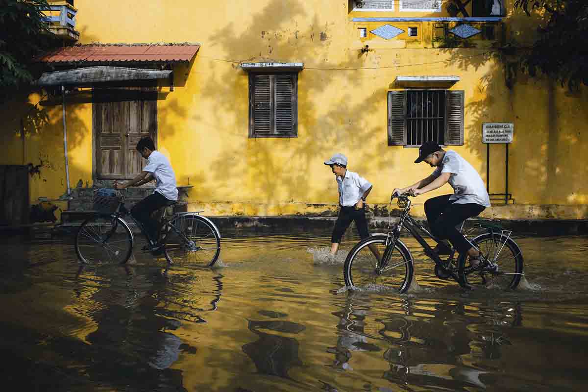 Unos niños van a la escuela por unas calles anegadas en Vietnam. Cambio climático / Foto: Pixabay