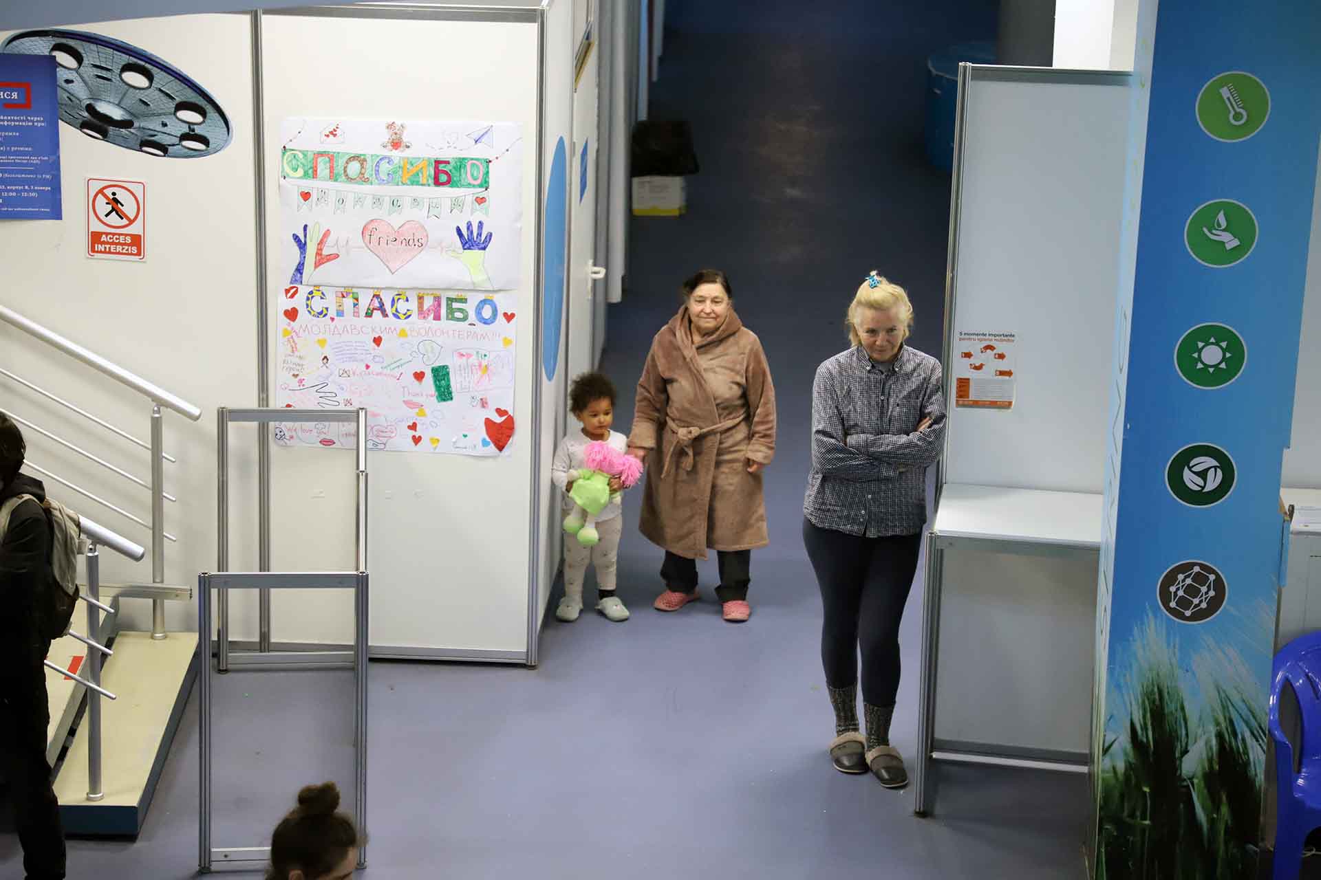 Dos mujeres y una niña contemplan como juegan otras niñas y niños ucranianas en el interior de uno de los pabellones de MoldExpo, en Chisináu (Moldavia)  / Foto: FFM - EA