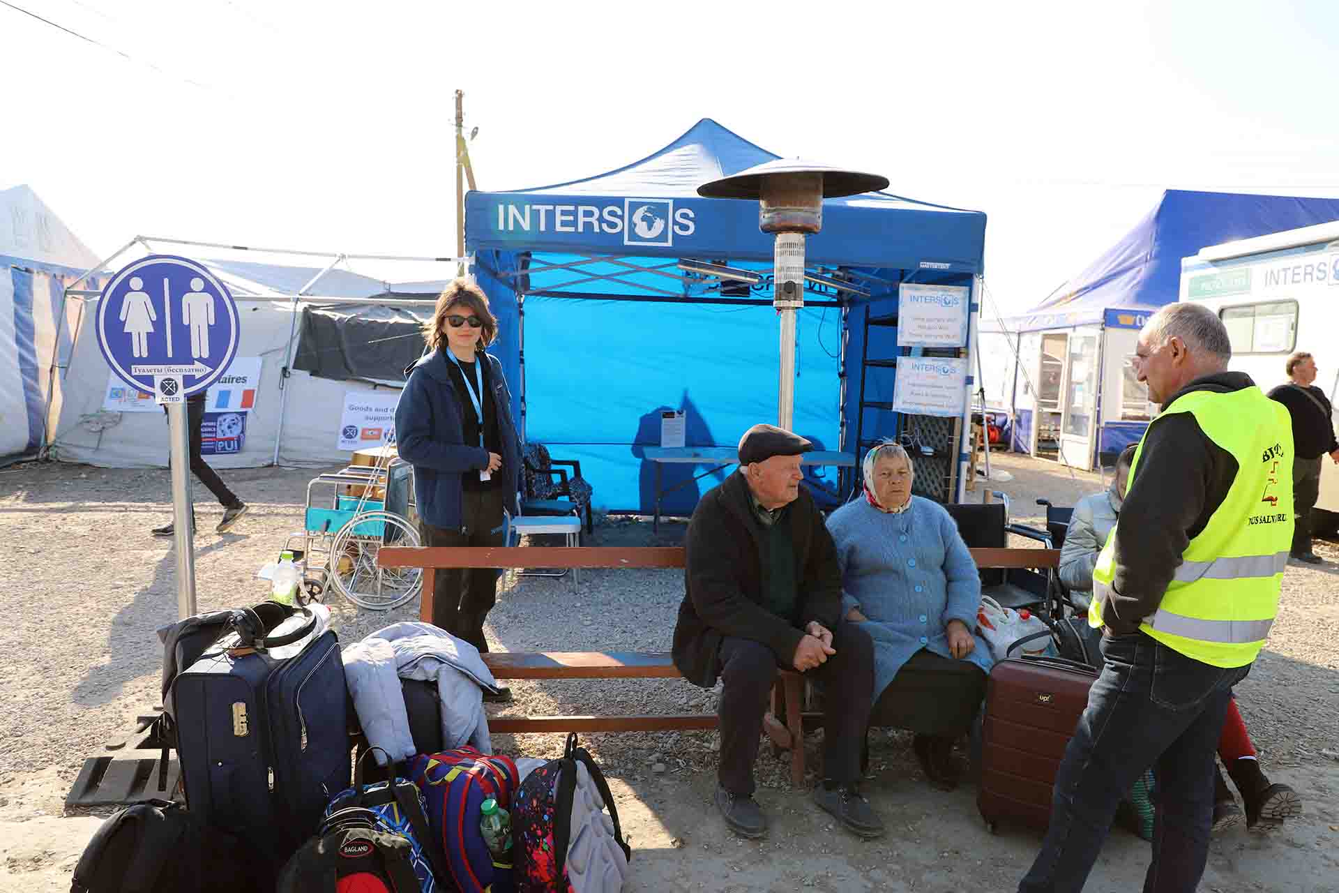 Dos personas ancianas esperan en Palanca que llegue un transporte. A su lado la voluntaria Daniela Ionita de Intersos observa que cualquier necesidad que pueda surgir  / Foto: FFM - EA