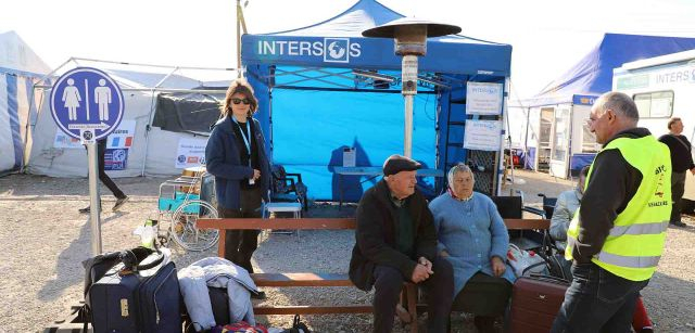 Dos personas ancianas esperan en Palanca que llegue un transporte. A su lado la voluntaria Daniela Ionita de Intersos observa que cualquier necesidad que pueda surgir  / Foto: FFM - EA