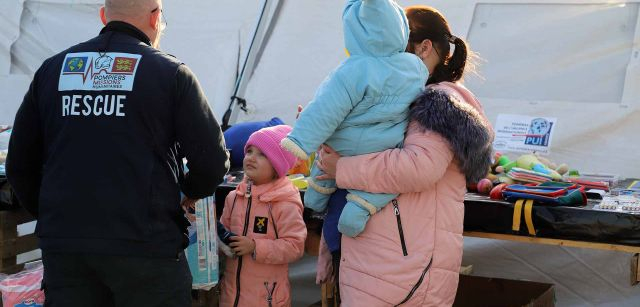 Un bombero atiende a una niña ucraniana en Palanca, la frontera de Moldavia con Ucrania / Foto: FFM - EA