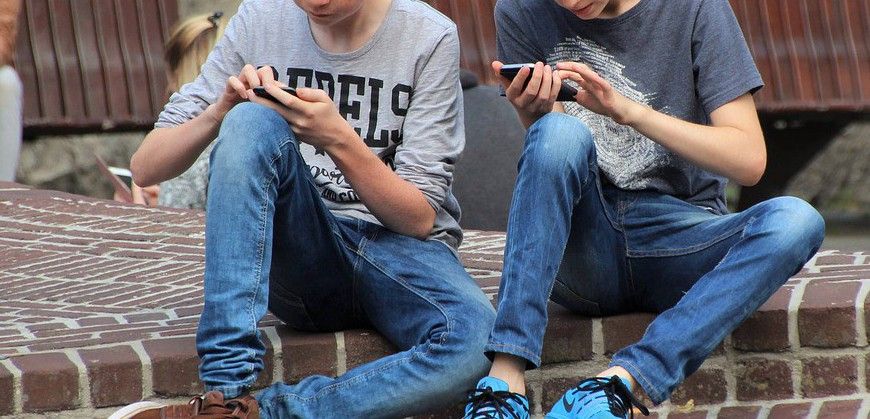 Dos niños jugando a Pokemon con sus teléfonos en la calle / Foto: Natureaddict