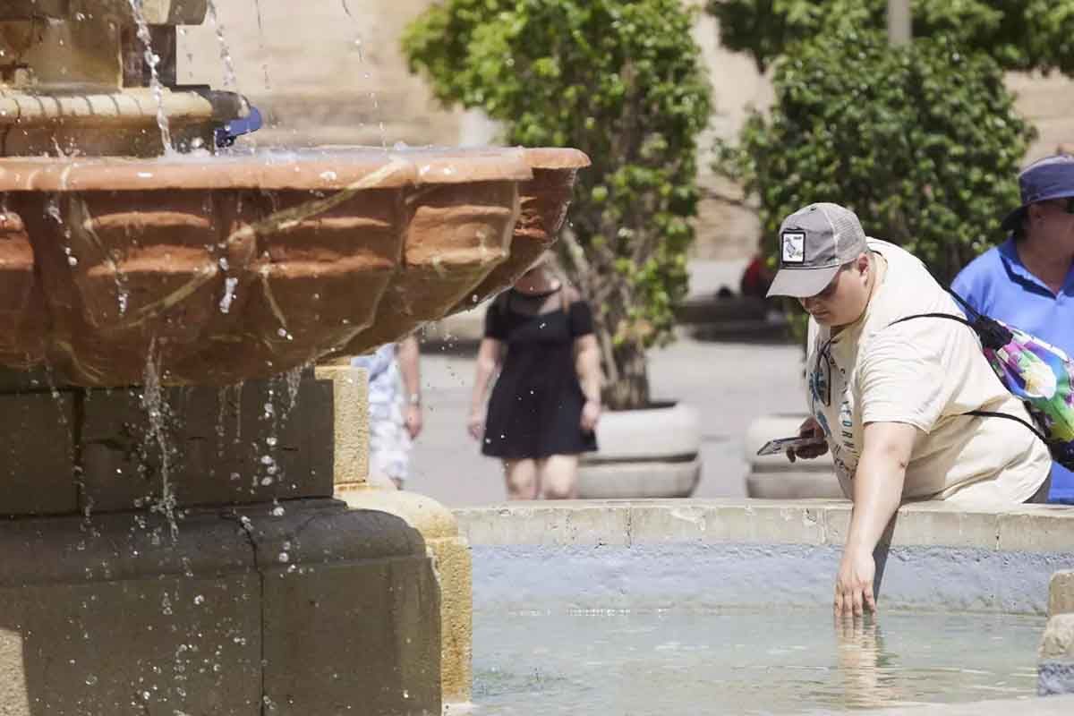 Un señor introduce la mano en una fuente para refrescarse durante el primer día de altas temperaturas en Sevilla, a 19 de mayo de 2022 en Sevilla (Andalucía, España)