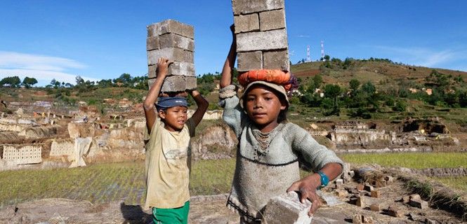 Dos niños de seis años transportan peligrosamente sobre sus cabezas ladrillos en Antsirabe, Madagascar / Foto: OIT 
