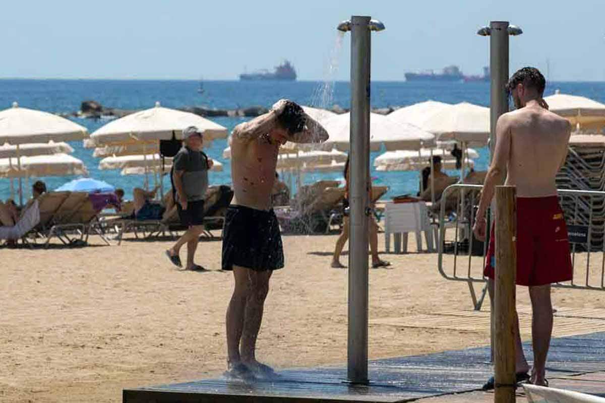 Dos personas se mojan en las duchas de la playa de la Barceloneta, a 13 de julio de 2022, en Barcelona, Catalunya (España) / Foto: EP