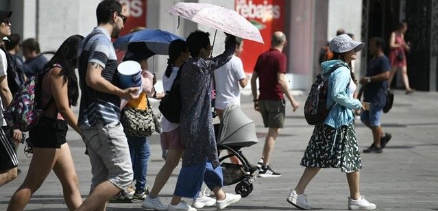 Un grupo de turistas se protegen del sol en el centro de Madrid antes de la pandemia / Foto: Óscar del Pozo - EP