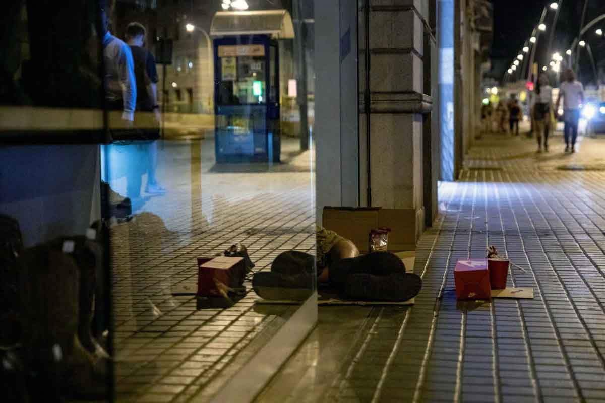 Una persona duerme a las puertas de una zapatería en Barcelona. Ola de calor / Foto: EP