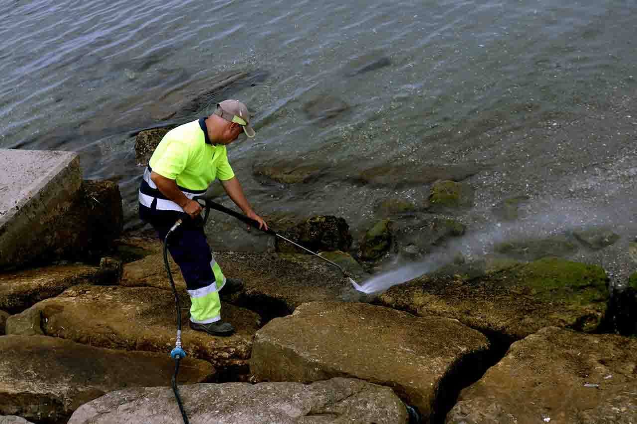 Un operario limpia las rocas manchadas en la playa de Poniente de La Línea con el vertido del OS35 / Foto: EP