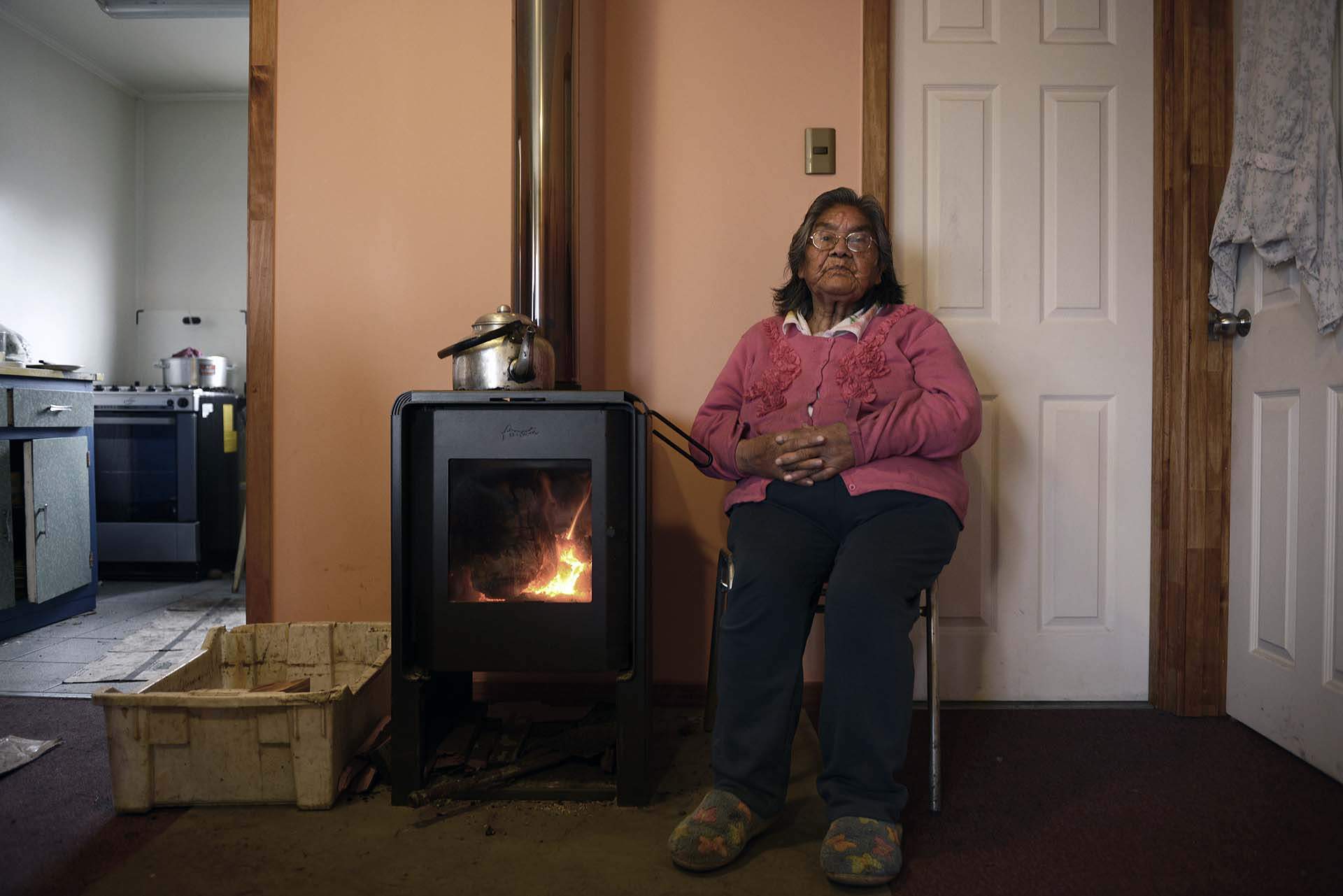 Cristina Calderón, la última hablante del milenario idioma de los yaganes, junto a la lumbre en su domicilio de Villa Ukika / Foto: Alfons Rodríguez