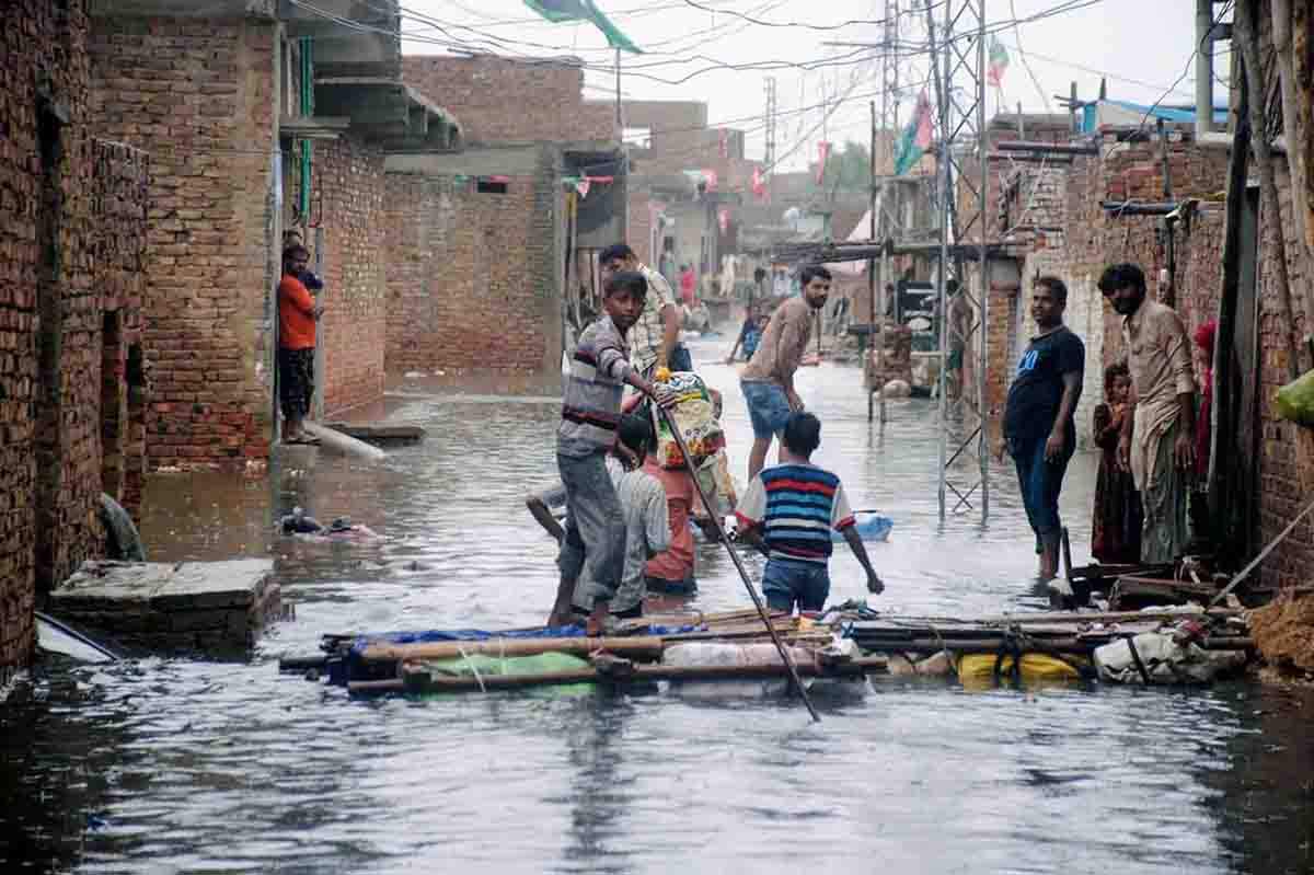 Personas caminan por un camino inundado después de que las lluvias monzónicas sumergieron el área, Hyderabad (Pakistán). Cambio climático / Foto: EP