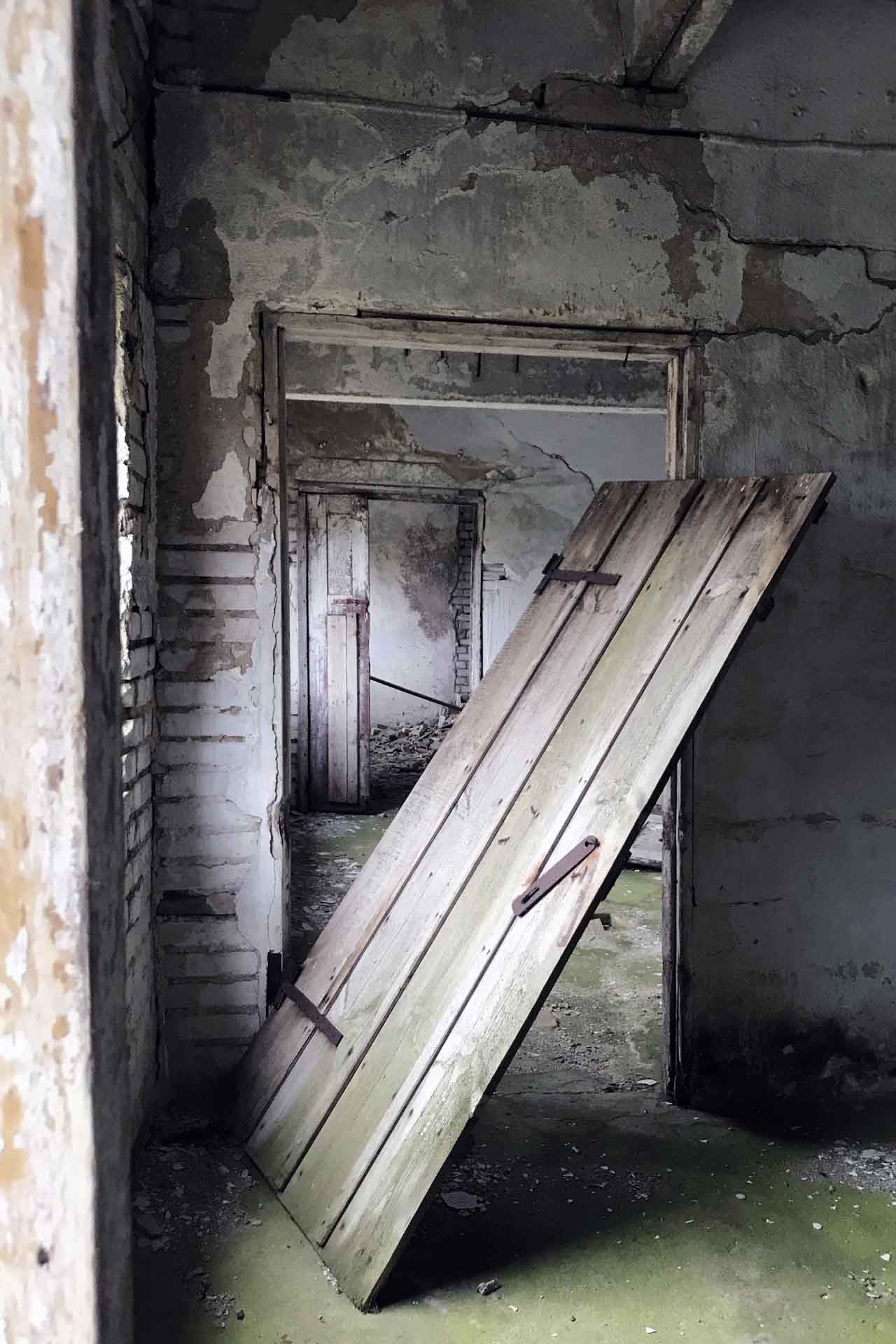 Una puerta cuelga de sus bisagras en un edificio agrícola abandonado en el centro de Estonia, en el antiguo emplazamiento de una gran granja colectiva de la época soviética / Foto: Capitán Swing