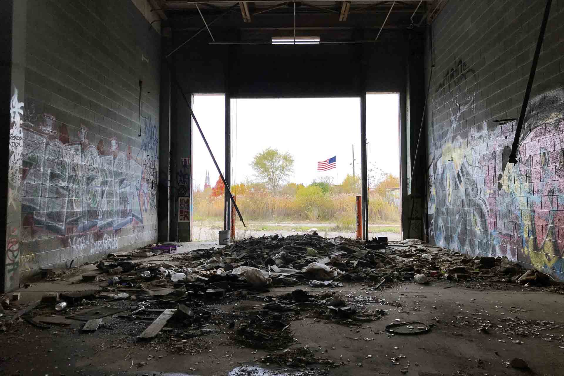 Las barras y estrellas ondean al viento, como se aprecia desde un almacén abandonado en Detroit (EE UU) / Foto: Capitán Swing