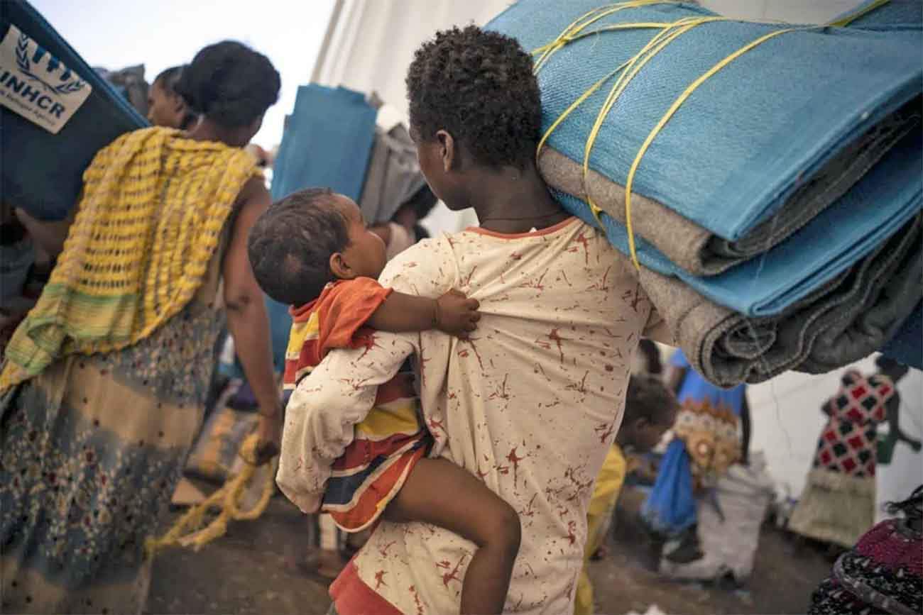Una refugiada etíope con su bebé recibe esteras y cobijas en un centro de tránsito en Hamdayet, Sudán. Crisis humanitaria / Foto: ACNUR