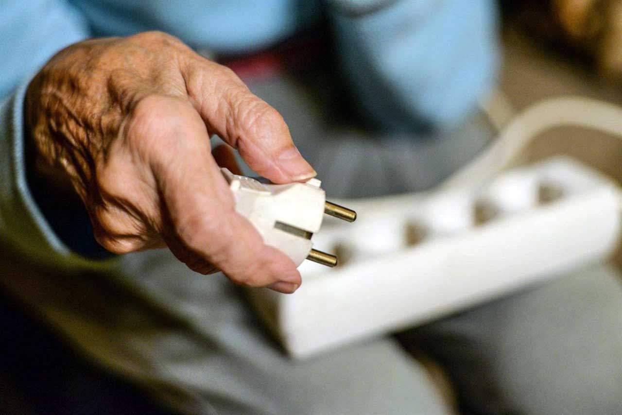 Un anciano sostiene un enchufe en su mano. Pobreza energética / Foto: EP