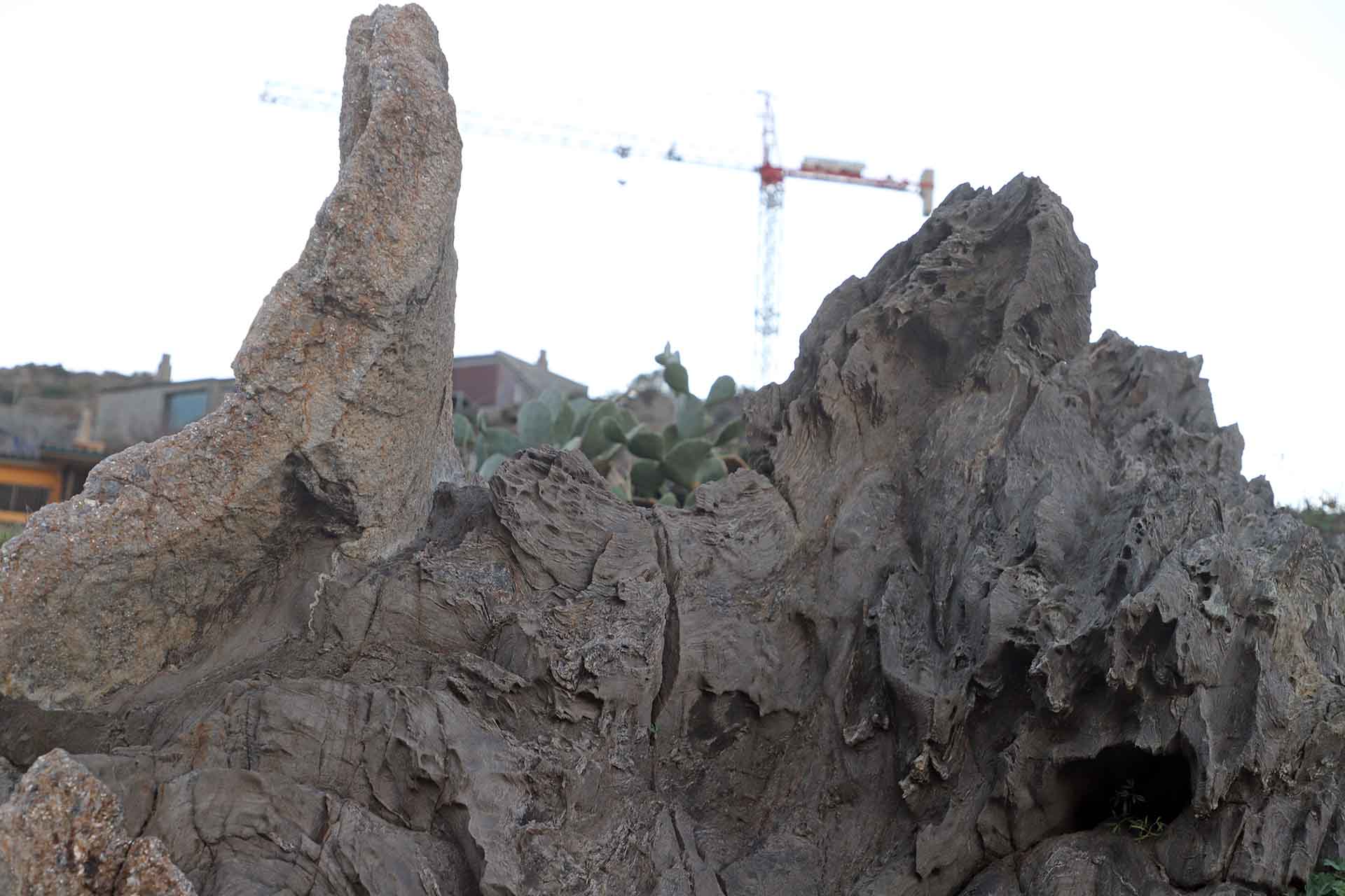 Roca esculpida por el viento y los microfragmentos de piedra con una grúa torre para la construcción que tanto amenaza la costa, en cala Tamariua en el Cap de Creus en Catalunya (España) / Foto: FFM - EA