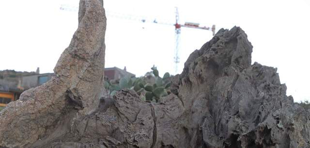 Roca esculpida por el viento y los microfragmentos de piedra con una grúa torre para la construcción que tanto amenaza la costa, en cala Tamariua en el Cap de Creus en Catalunya (España) / Foto: FFM - EA