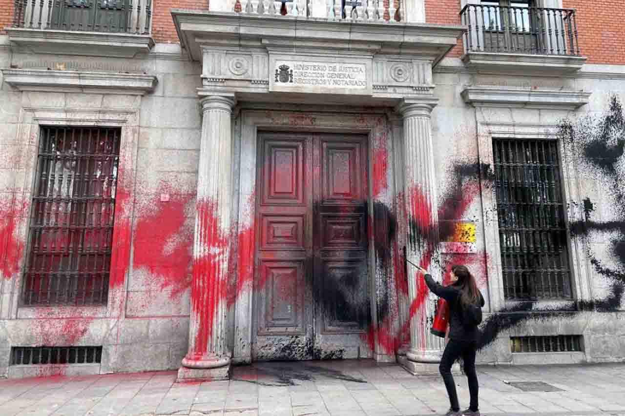 Una activista rocía tintes rojo y negro la fachada del edificio del Ministerio de Justicia / Foto: FV