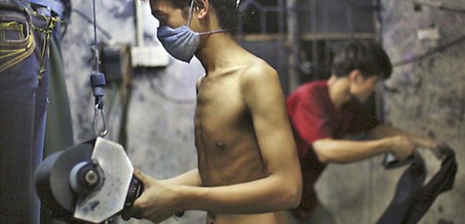 Trabajadores desgastando tela vaquera en un taller / Foto: CRL