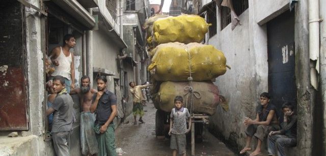 Un grupo de menores transporta un cargamento de cazuelas por las calles de la vieja Daca / Foto: Fundación Educo