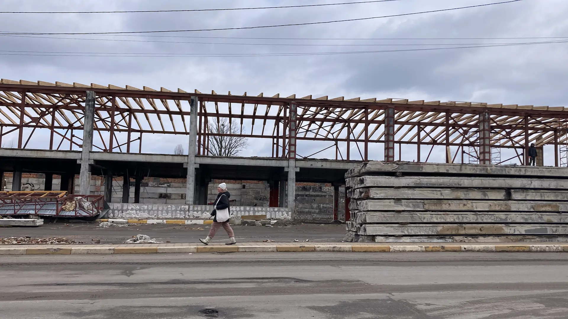 Una mujer cruza la calle y, detrás un puente destruido en reconstrucción en Irpin, Ucrania / Foto: AG - EA