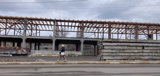 Una mujer cruza la calle y, detrás un puente destruido en reconstrucción en Irpin, Ucrania / Foto: AG - EA