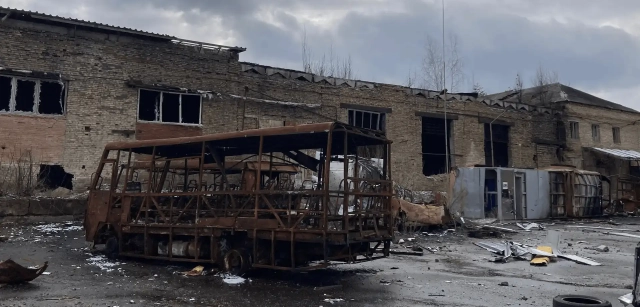 Estructura calcinada de un vehículo de transporte colectivo, detrás las ruinas de un edificio destruido a causa de la explosión de una bomba en Irpin en el noreste de Ucrania / Foto: AG - EA