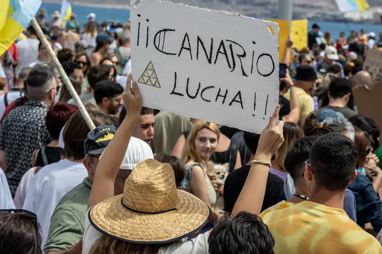 Una persona sujeta un cartel de protesta durante una manifestación contra el modelo turístico, a 20 de abril de 2024, en Las Palmas de Gran Canaria, Gran Canaria, Canarias (España) / Foto: EP