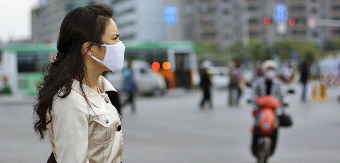 Una mujer china se protege con una mascarilla / Foto: Barnaby Chambers