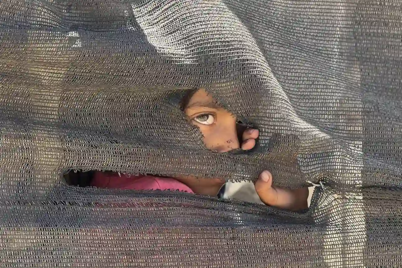 Una niña se asoma tras una tienda improvisada en el puerto en la Ciudad de Gaza / Foto: EFE/ Ahmad Awad
