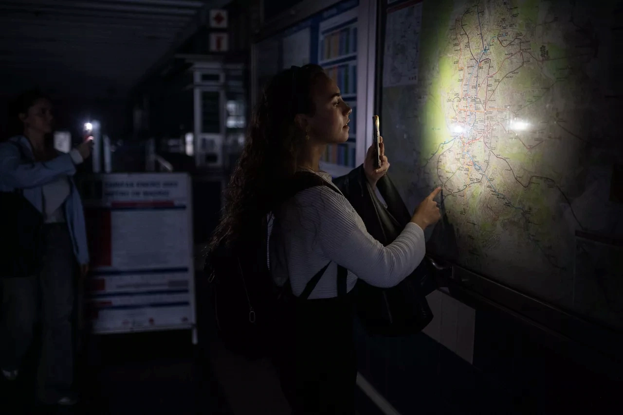 Una mujer alumbra con su móvil el plano del Metro de Madrid durante el apagón del 28 de abril de 2025 / Foto: EP