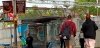 Personas esperan en una parada de autobús en La Farga de L’Hospitalet bajo un cartel de BioCultura Barcelona 2026 / Foto: EA
